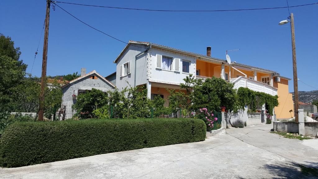 a white and orange house with a hedge in front of it at Apartments Anka in Vinišće