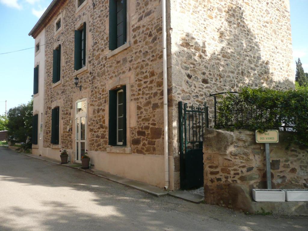 a brick building with a gate on a street at LES TERRES BASSES in Fabrezan