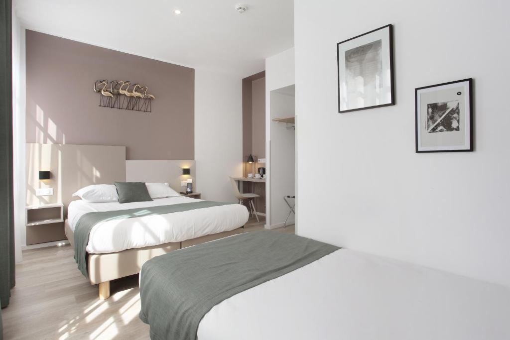 a hotel room with two beds and a desk at Hôtel Alcôve Nice in Nice