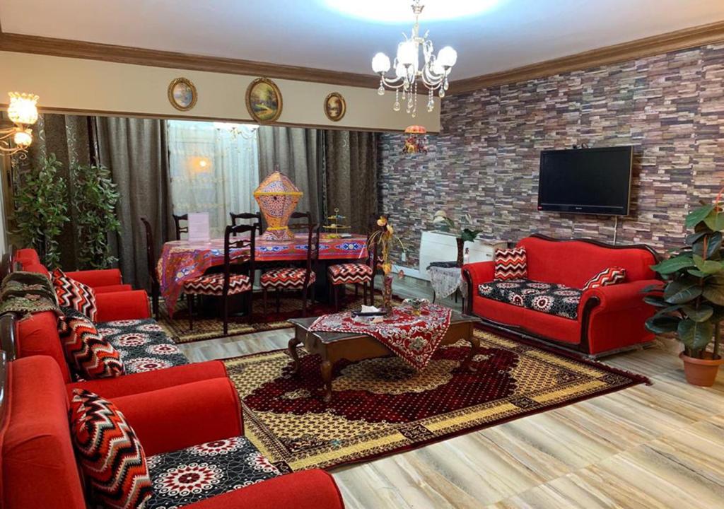 Il comprend un salon doté d'un mobilier rouge et d'un mur en briques. dans l'établissement Luxury Apartment City stars, au Caire