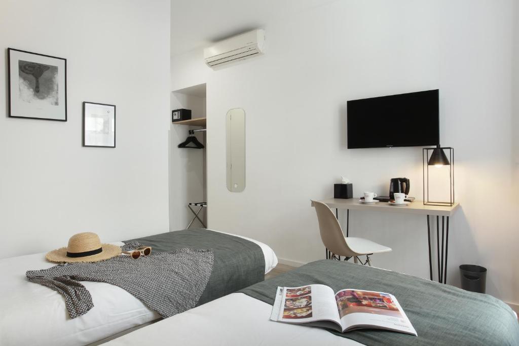 a bedroom with a bed with a hat and a desk at Hôtel Alcôve Nice in Nice