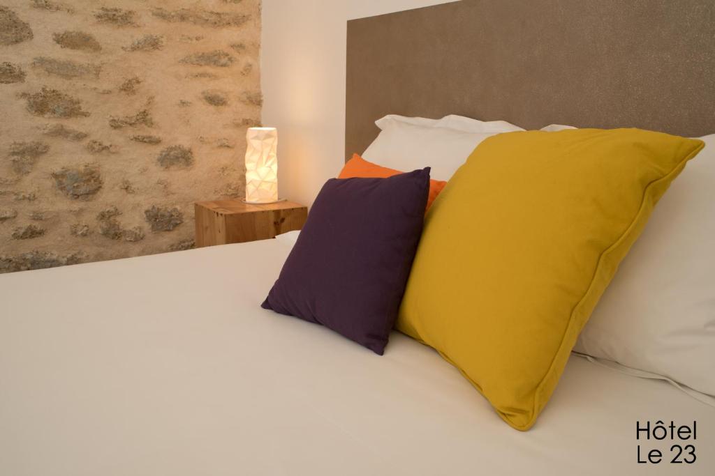 a bed with four pillows on it with at Hôtel Le 23 in Sauternes