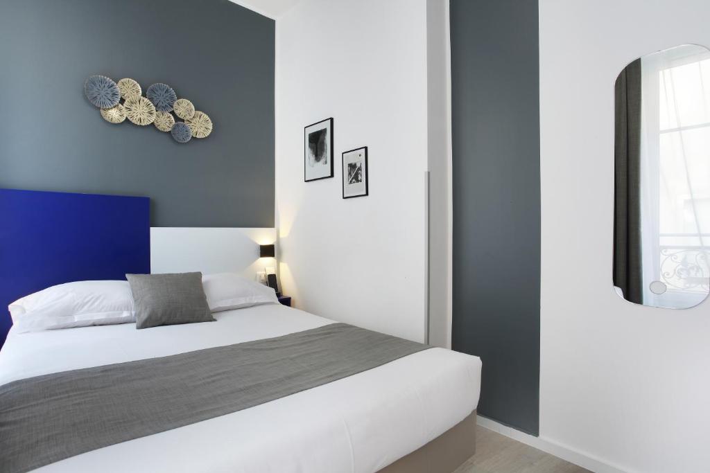 a bedroom with a white bed and a blue wall at Hôtel Alcôve Nice in Nice