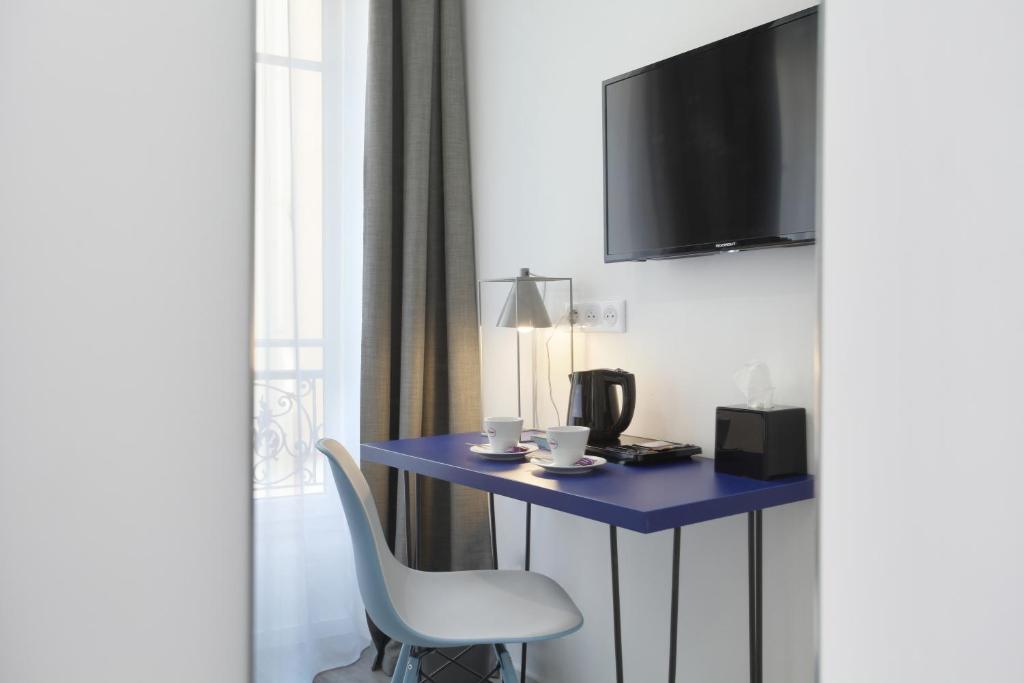 a room with a table and a chair and a tv at Hôtel Alcôve Nice in Nice