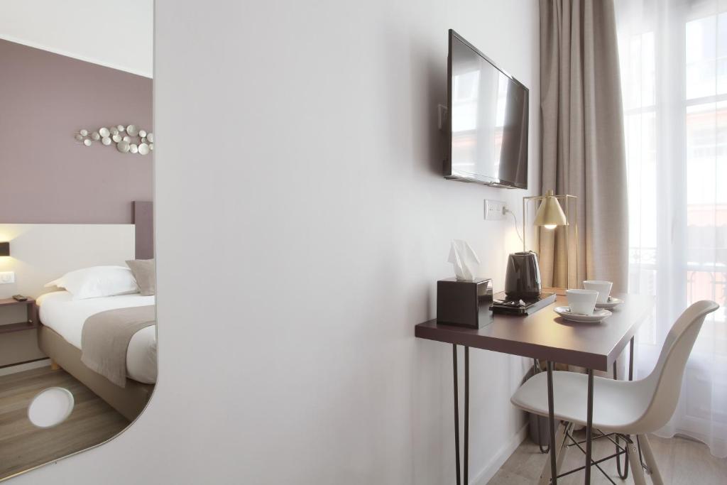a hotel room with a desk and a bed and a mirror at Hôtel Alcôve Nice in Nice