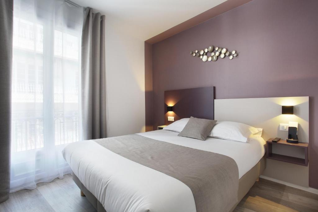 a bedroom with a large bed and a large window at Hôtel Alcôve Nice in Nice