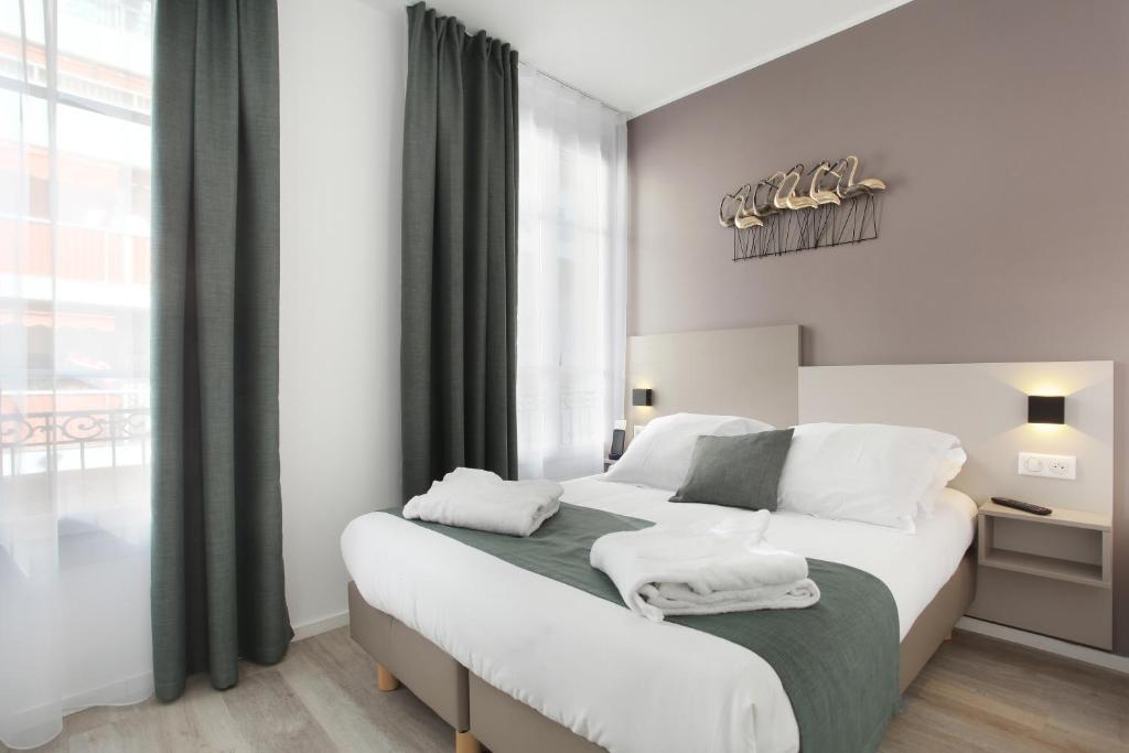 a bedroom with a large white bed with a window at Hôtel Alcôve Nice in Nice
