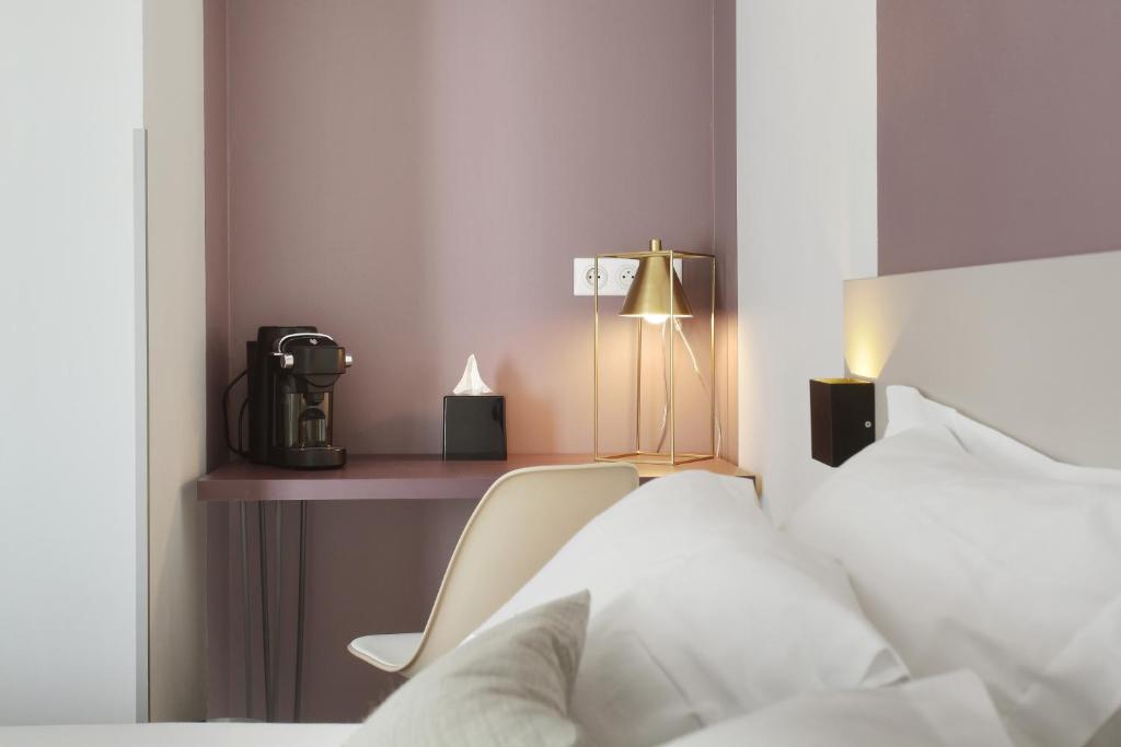 a bedroom with a bed and a desk with a lamp at Hôtel Alcôve Nice in Nice