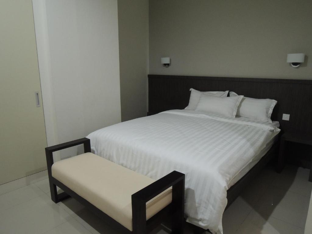 1 dormitorio con 1 cama blanca grande y 1 silla en Harlys Residence, en Yakarta