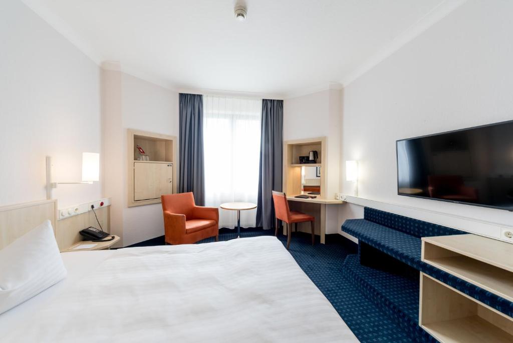 a hotel room with a bed and a flat screen tv at IntercityHotel Magdeburg in Magdeburg