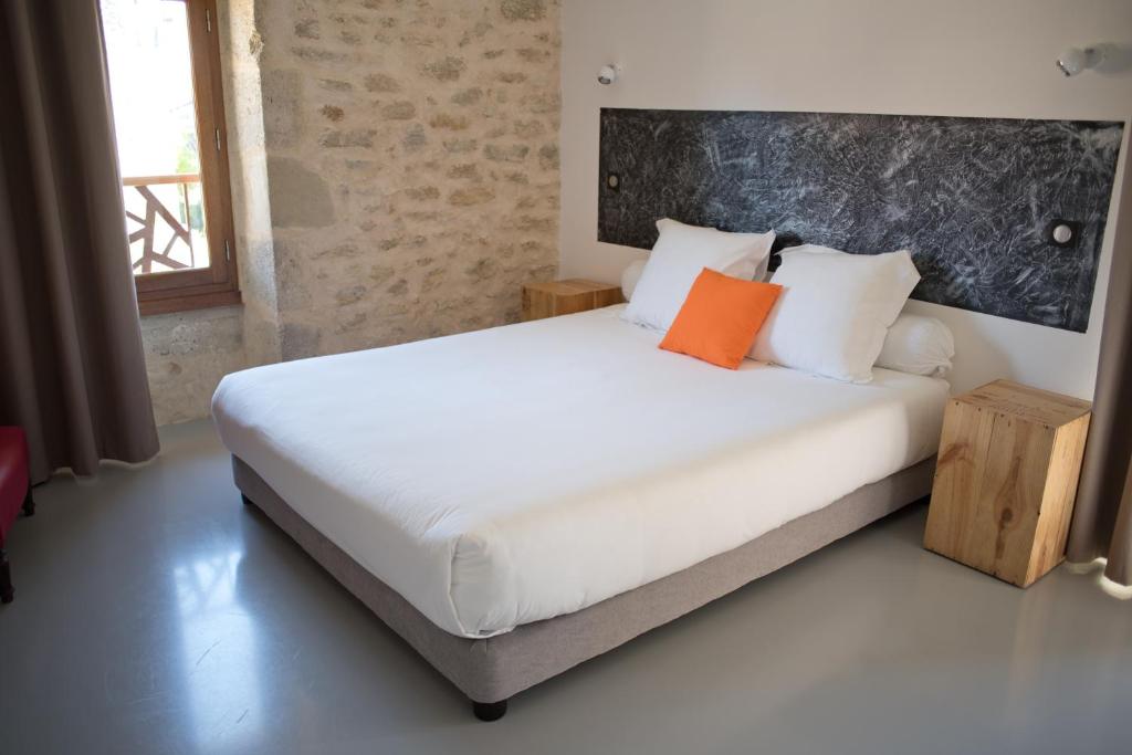 a bedroom with a large white bed with orange pillows at Hôtel Le 23 in Sauternes