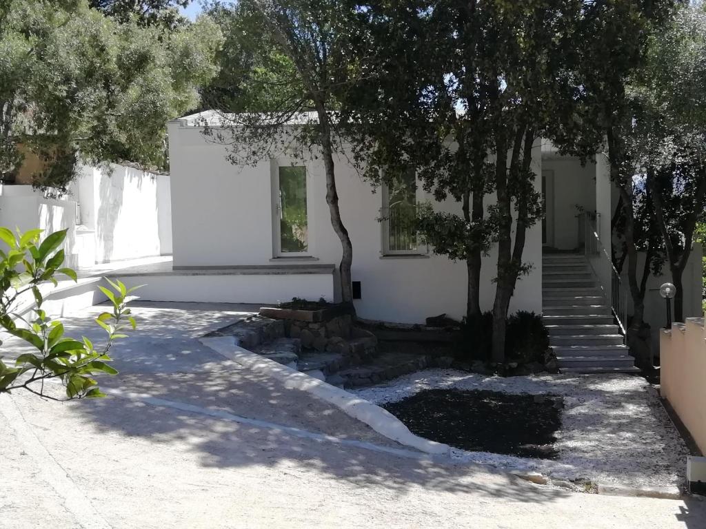 a white house with stairs and trees in the yard at in campagna da Nino in Olbia