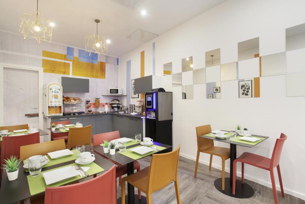 a dining room with tables and chairs and a kitchen at Hôtel Alcôve Nice in Nice
