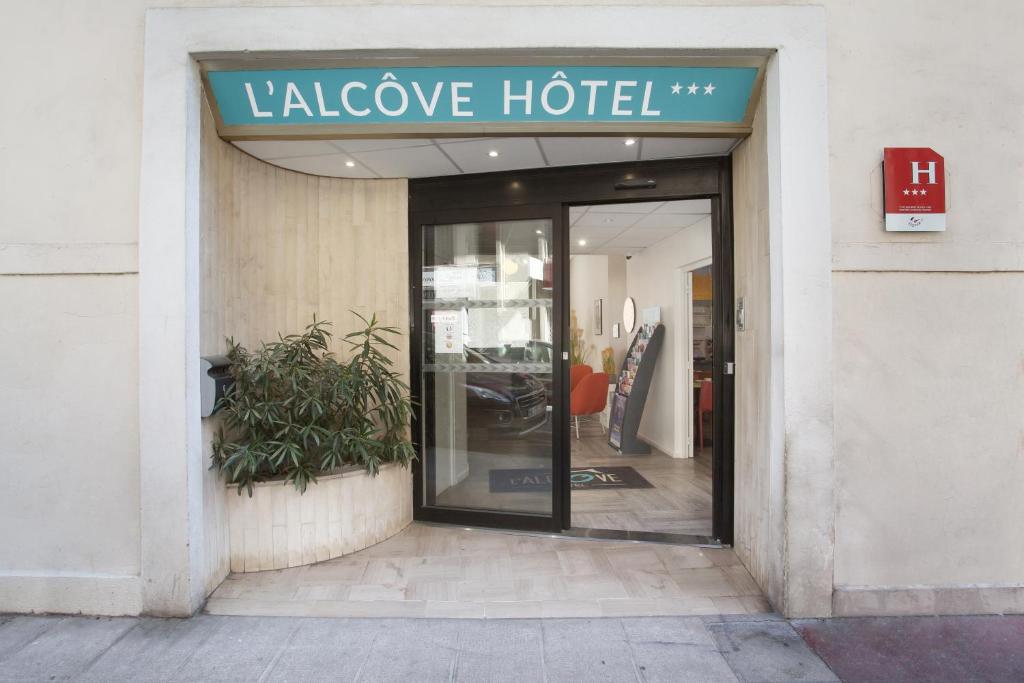 a glass door to a large hotel with a sign on it at Hôtel Alcôve Nice in Nice