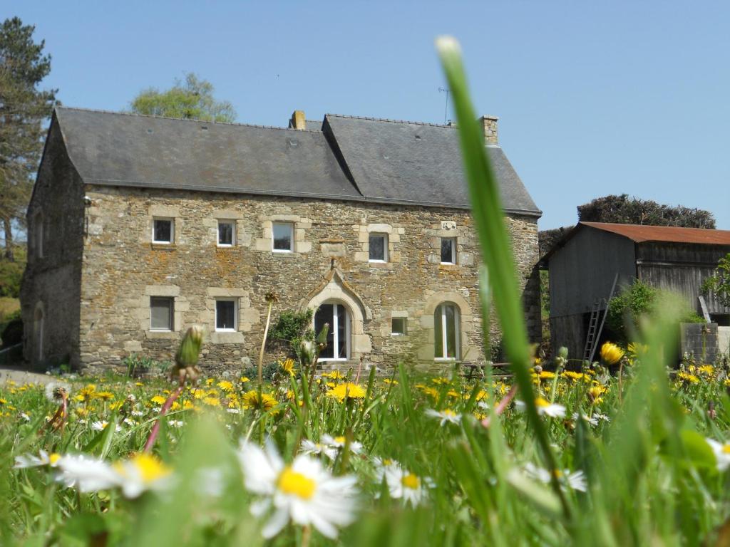 un ancien bâtiment en pierre avec un champ de fleurs dans l'établissement Manoir de Questinguy, à Allineuc