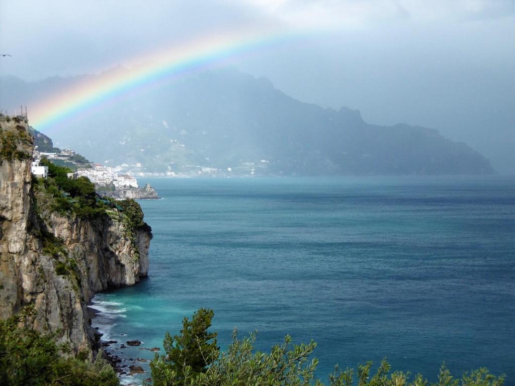 a rainbow over the ocean with a mountain at Blue Lagoon in Amalfi