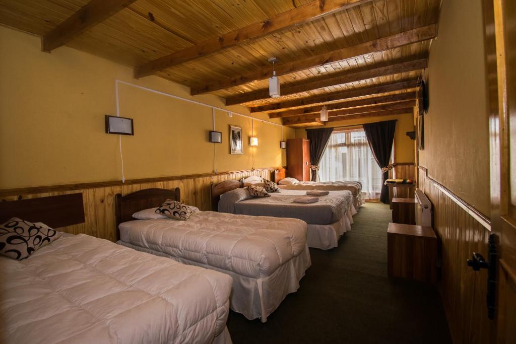 a row of three beds in a hotel room at Hostal Alcázar in Puerto Natales