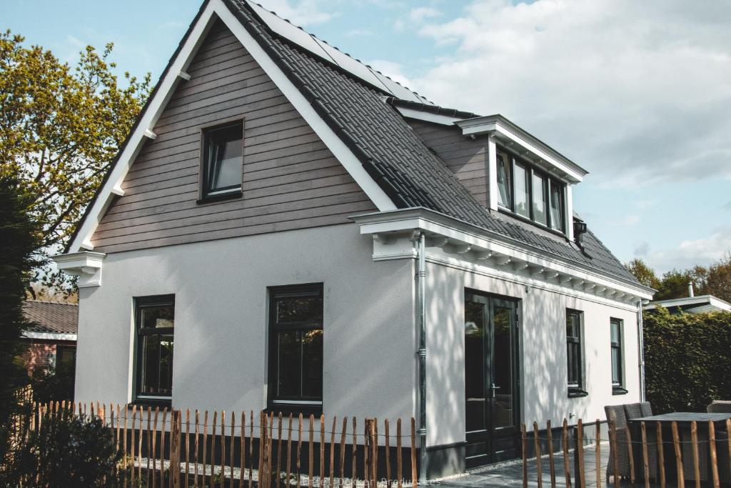 uma casa branca com um telhado preto em Huisje aan Zee em Oostkapelle