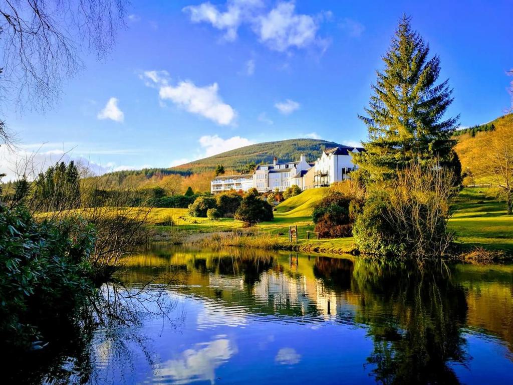 a house on top of a hill next to a lake at Macdonald Forest Hills Hotel & Spa in Aberfoyle