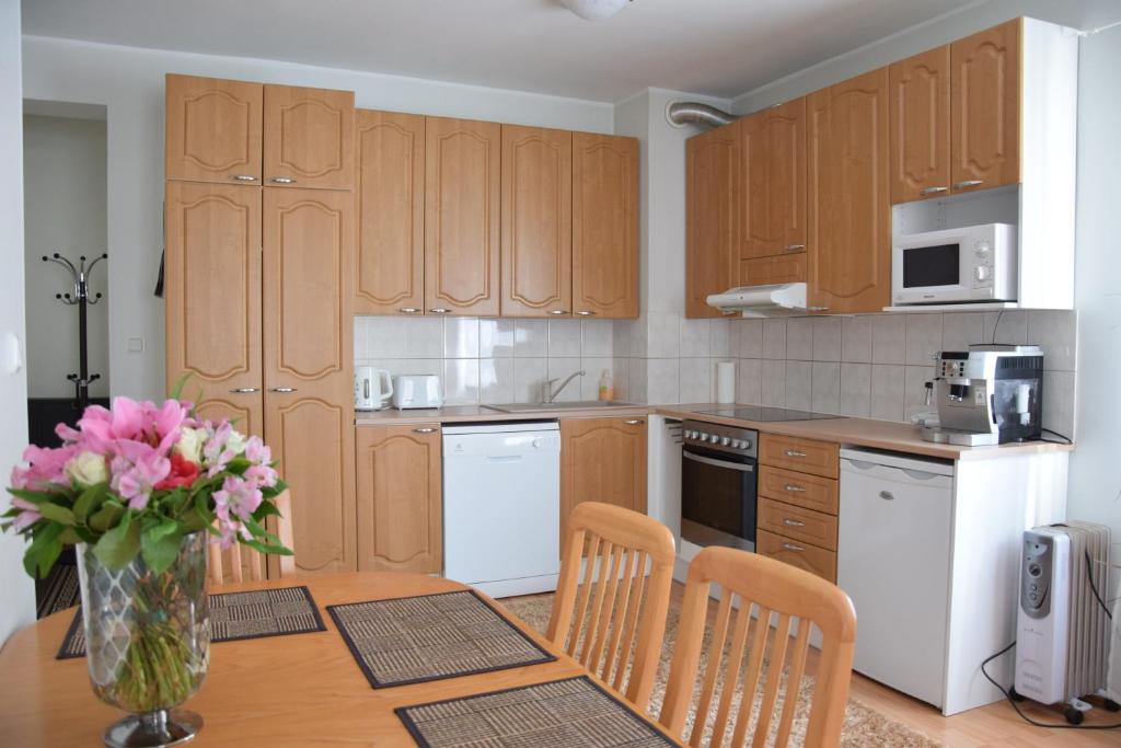 a kitchen with wooden cabinets and a table with a vase of flowers at Long Holiday Apartment in Kuressaare