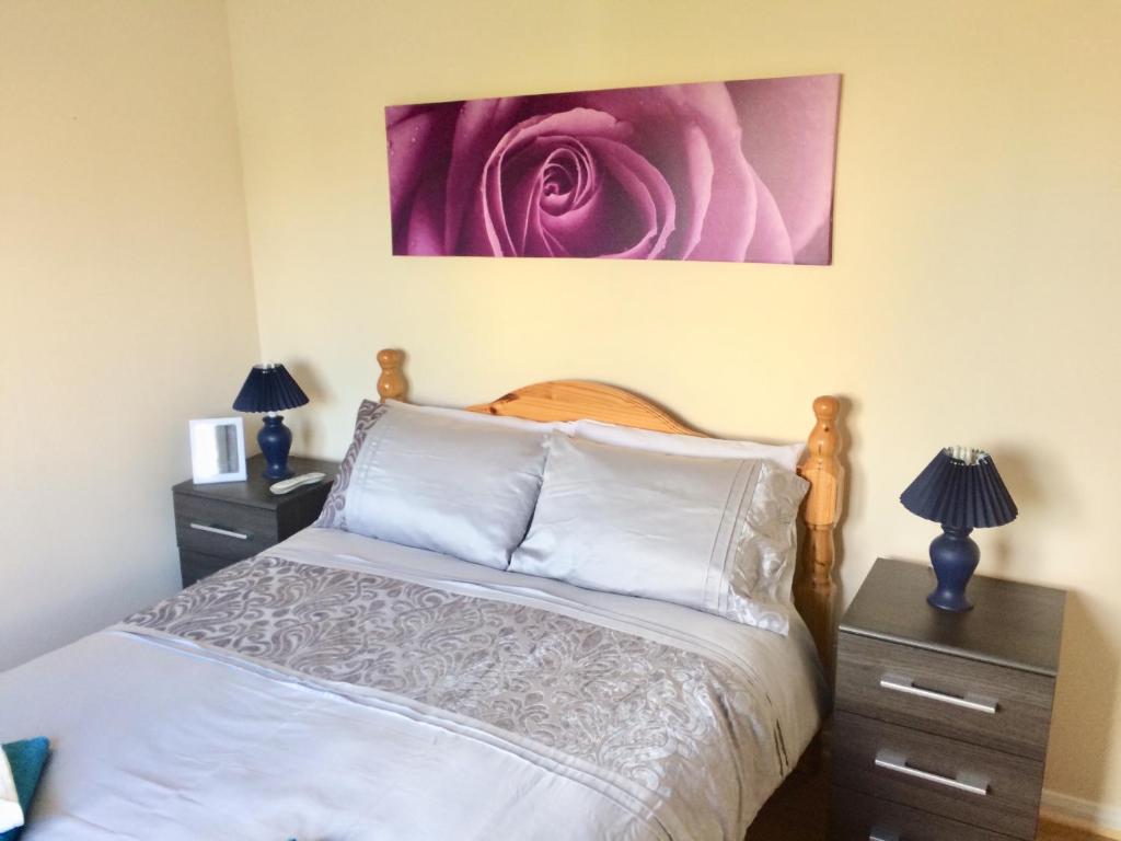 a bedroom with a bed with a pink rose painting on the wall at Invercaul House in Inverness