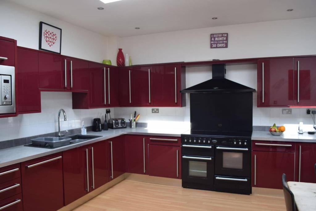 a kitchen with red cabinets and a black stove at Nottingham City House in Nottingham