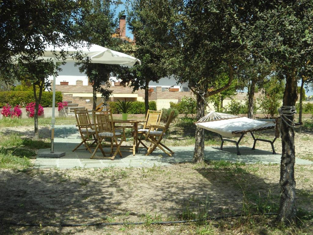 un patio con mesa, sillas y sombrilla en Tra Mare e Monti, en Santa Giusta
