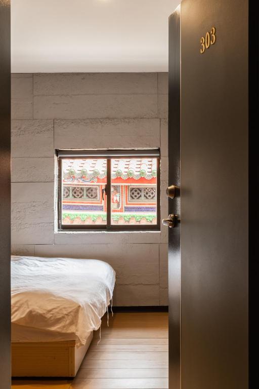 a bedroom with a bed and a window at Longshan Inn in Taipei