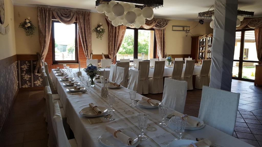 długi stół z białymi stołami i krzesłami w pokoju w obiekcie Pokoje i domki Saraceńska Chata w Stegnie