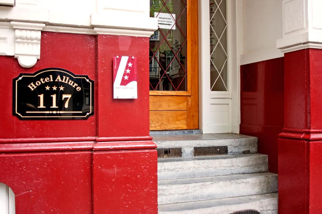 ein rotes Gebäude mit einer Tür und einem Schild darauf in der Unterkunft Hotel Allure in Amsterdam