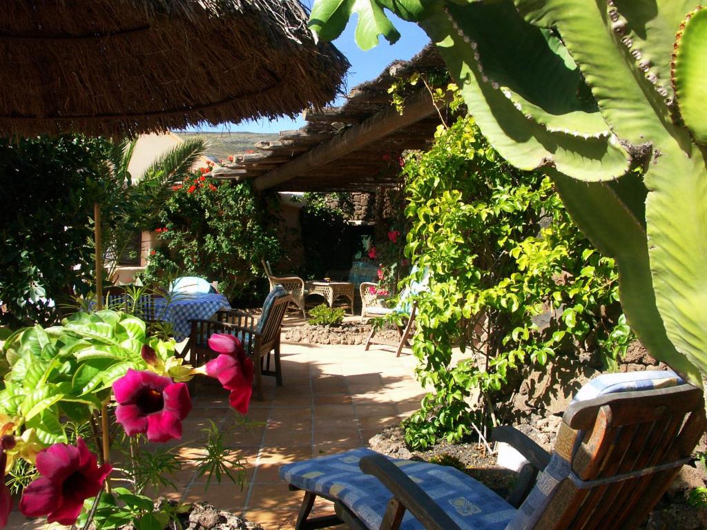 patio z krzesłami, kwiatami i parasolem w obiekcie Casa Niro w Tías
