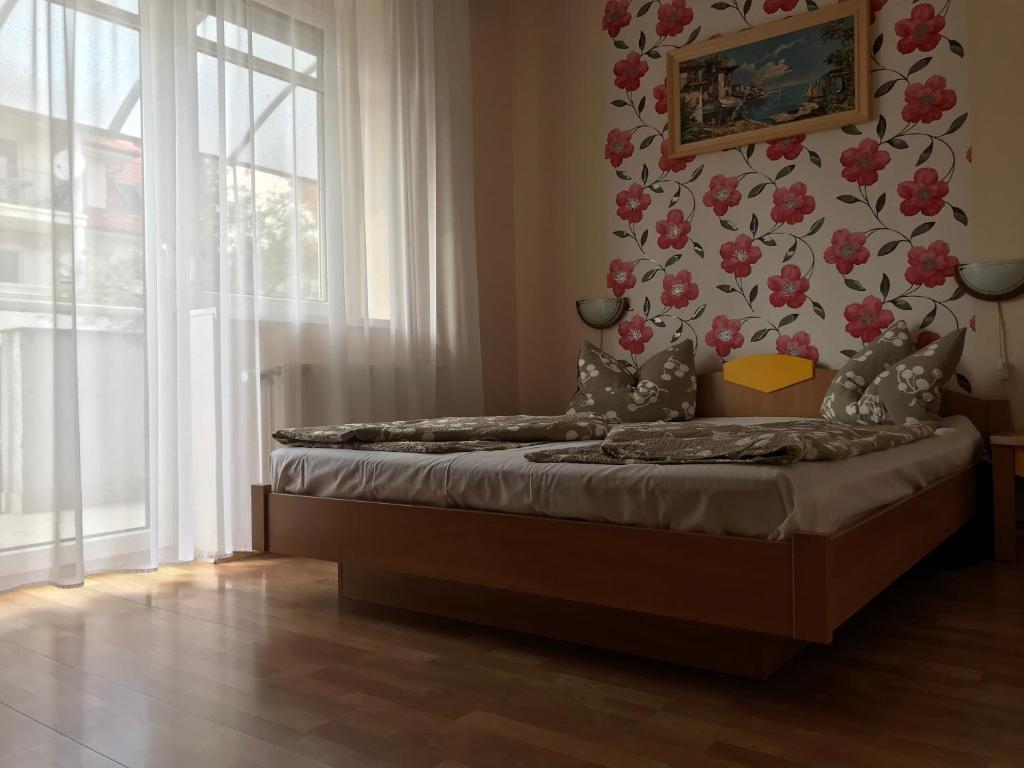 ein Schlafzimmer mit einem Bett mit Blumenwand in der Unterkunft József Attila Apartman Hajdúszoboszló in Hajdúszoboszló