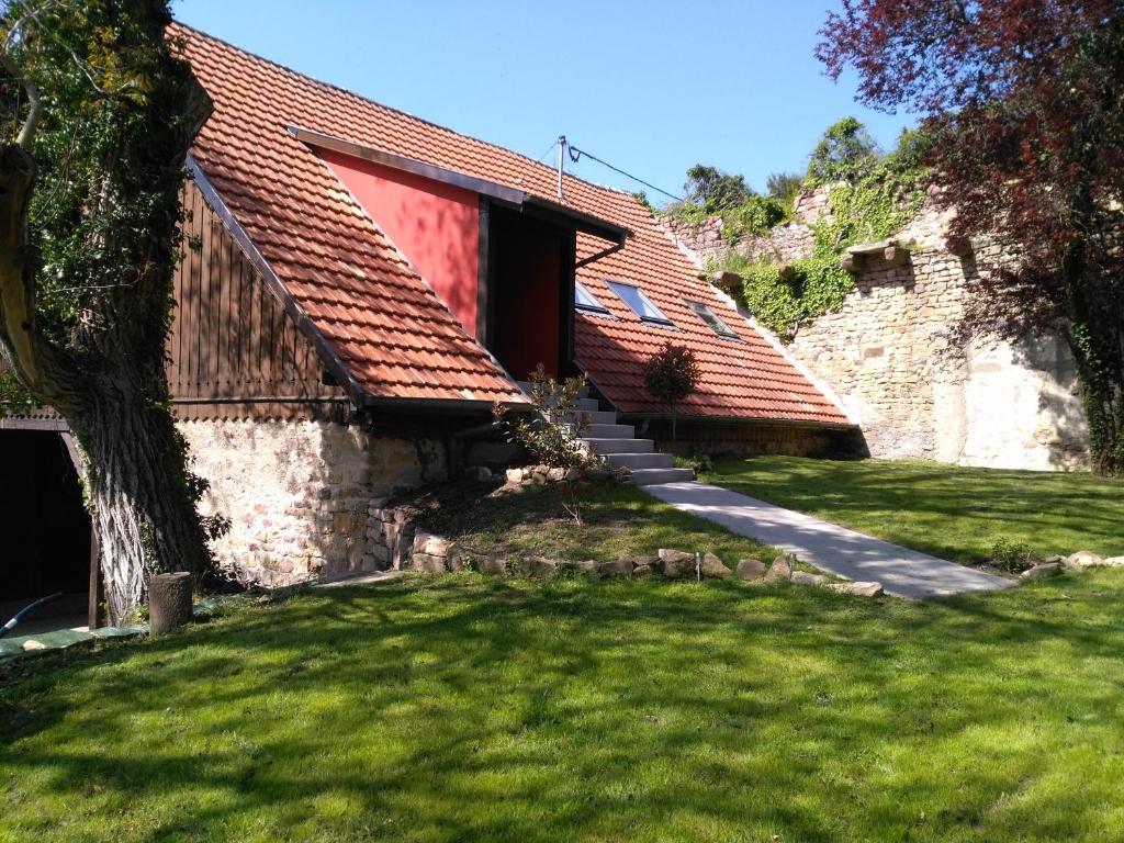 a house with a red roof and a grass yard at Joli gîte F2 indépendant avec jardin privé in Rouffach