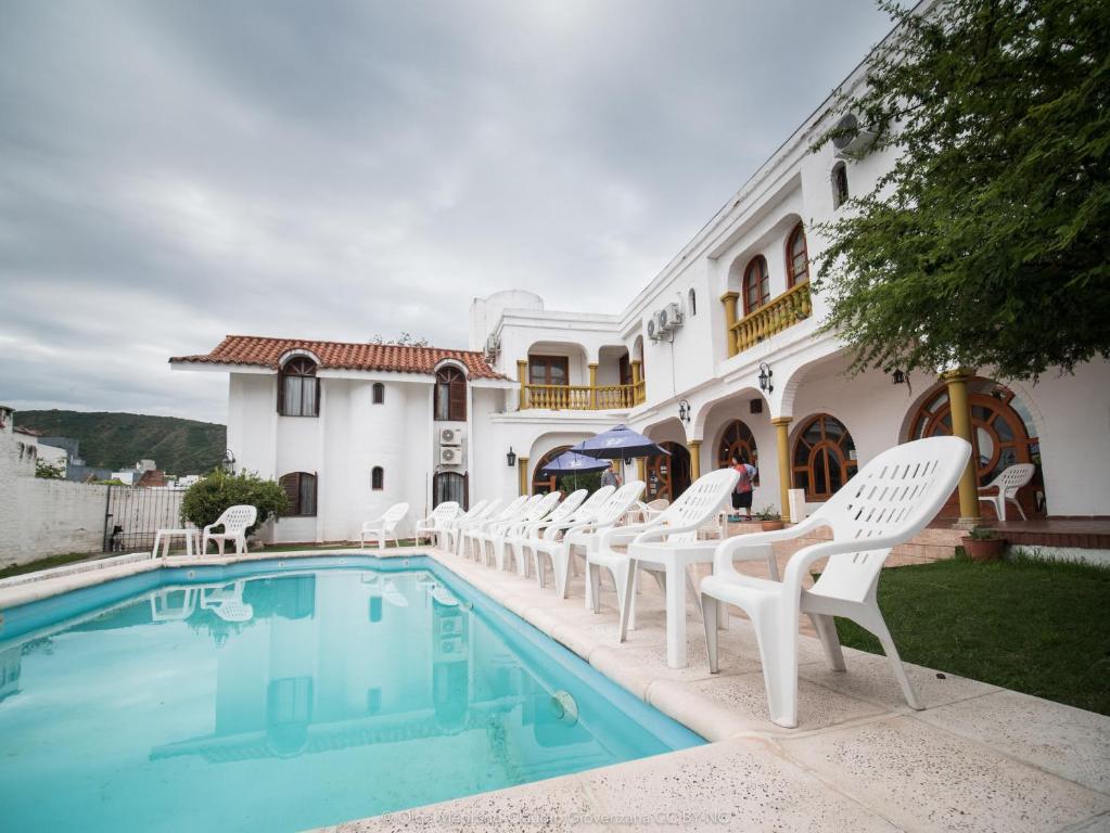 a group of white chairs sitting next to a swimming pool at Hotel Maspalomas in Villa Carlos Paz