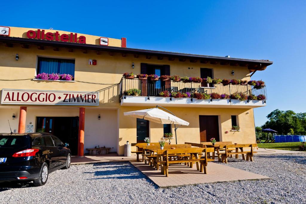 un edificio con tavoli e ombrelloni di fronte ad esso di Agriturismo Olistella a Palazzolo dello Stella