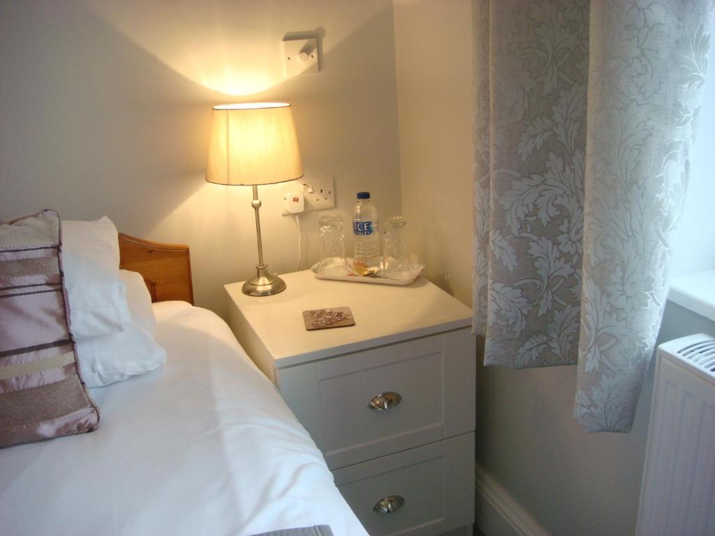 a bedroom with a bed and a lamp on a night stand at Broadlands Guest House in Stratford-upon-Avon