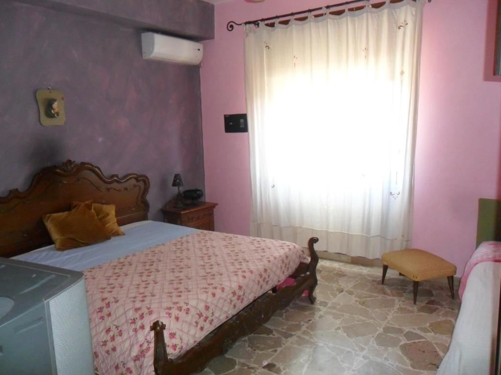 a bedroom with a bed and a window with pink walls at B&B PinkHouse in Milazzo