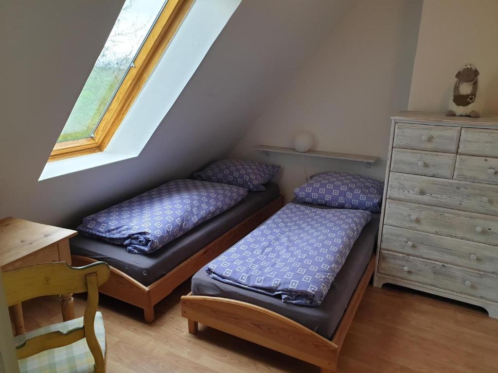 two beds in a room with a desk and a dresser at Schoppstuv in Tümlauer Koog