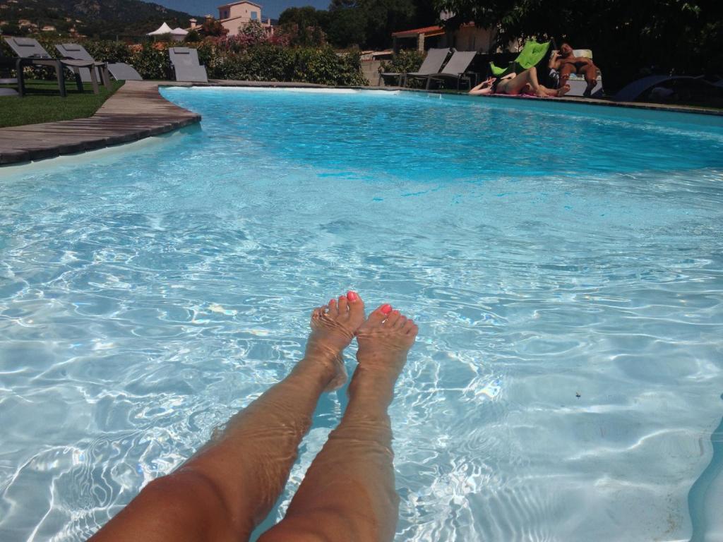 a person laying on their legs in a swimming pool at Hotel l'Isolella in Porticcio