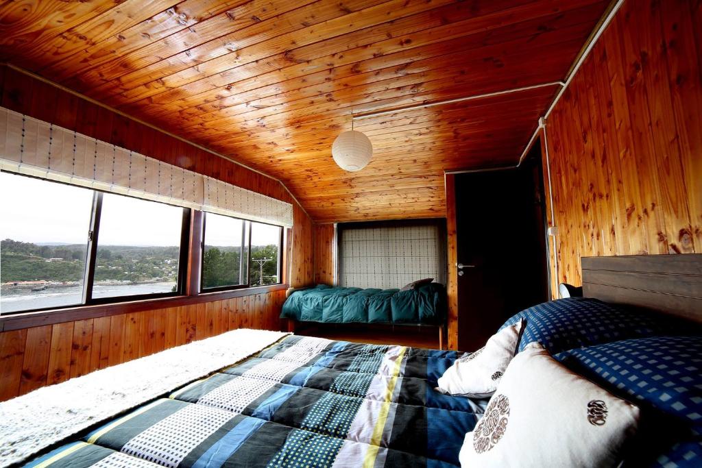 um quarto com uma cama num quarto de madeira com janelas em Hostería La Casa del Mar em Bahía Mansa