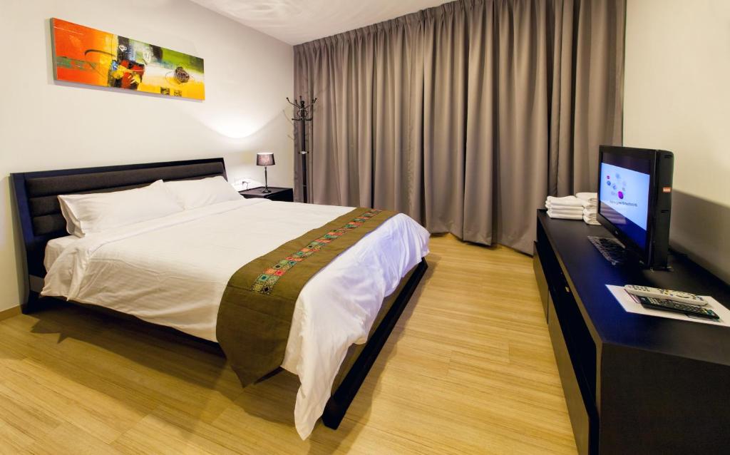 1 dormitorio con 1 cama y escritorio con TV en Luxfort 118 Service Suites, en George Town