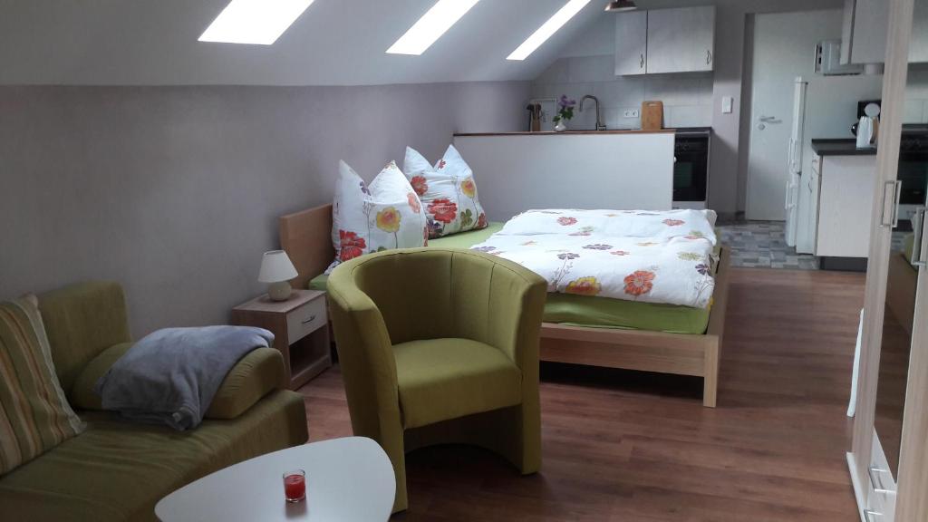 een slaapkamer met een bed, een stoel en een bank bij Fewo Abendsonne in Jannowitz