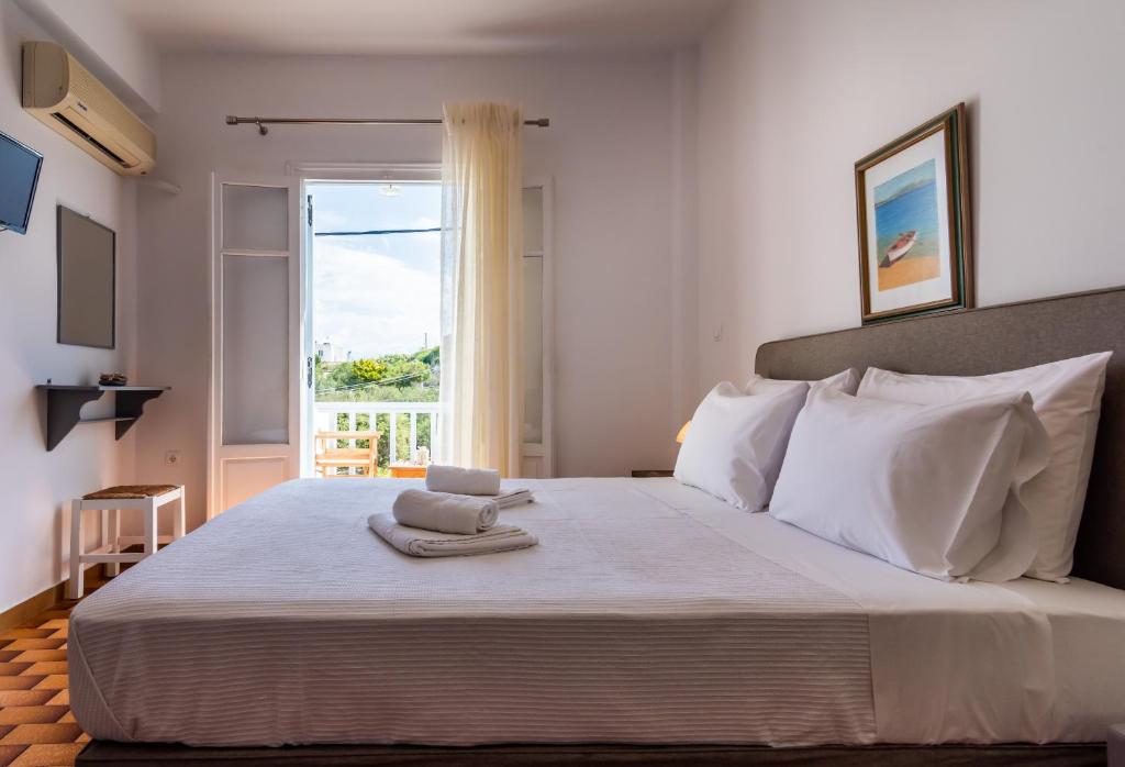 a bedroom with a large white bed with a window at Iliopoulou Studios in Pollonia