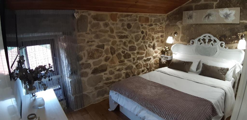 1 dormitorio con cama y pared de piedra en A Casiña Vella, en Poio