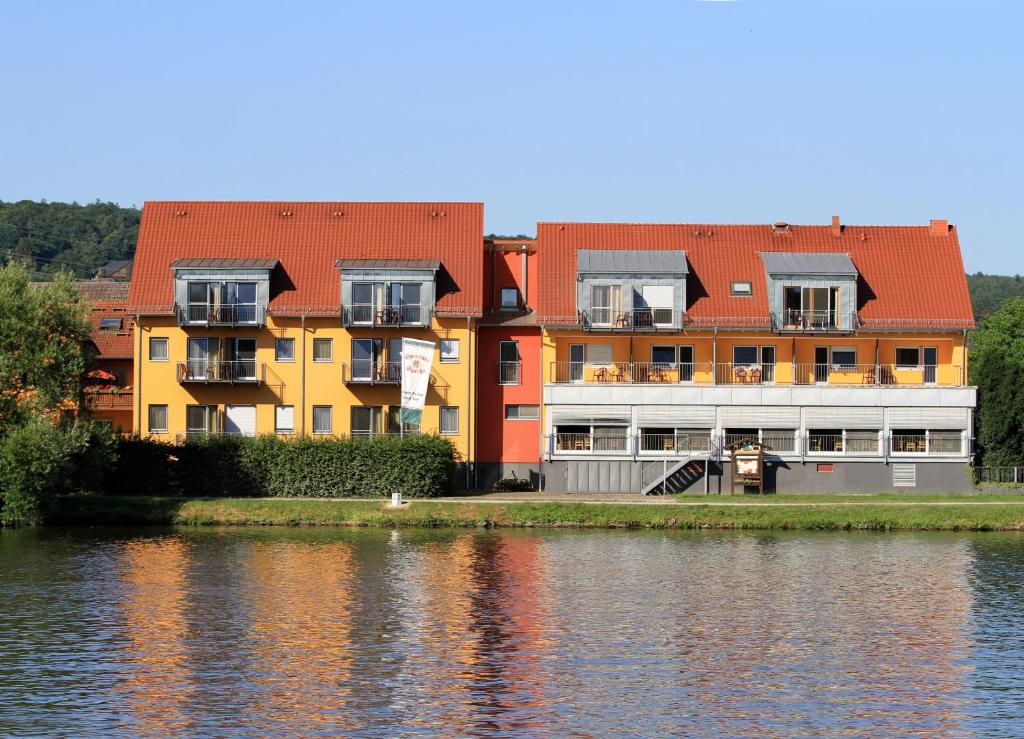 a row of buildings next to a body of water at Gasthof Zum Schwanen in Kleinostheim