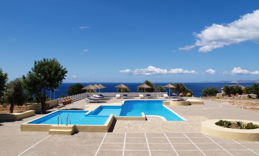 a pool at a resort with the ocean in the background at Mandilada Village in Marathokampos