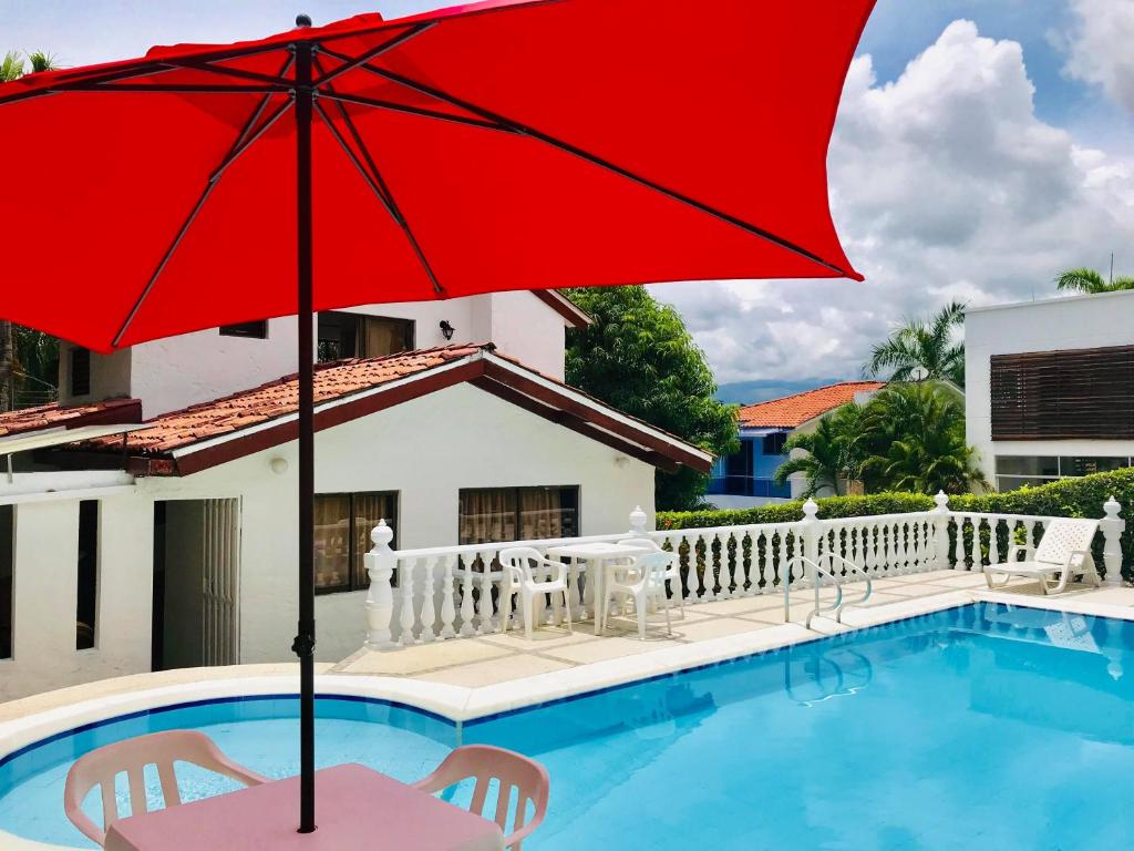 um guarda-chuva vermelho sentado ao lado de uma piscina em Casa Hacienda La Estancia piscina privada em Melgar