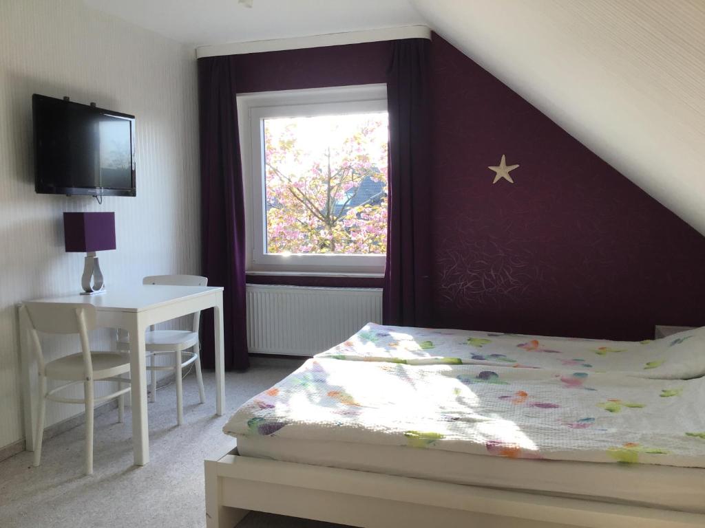 a bedroom with a bed and a table and a window at Ferienwohnung Seestern in Cuxhaven