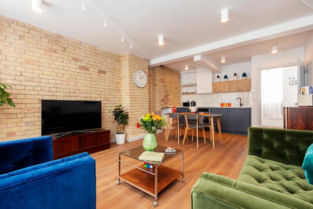 a living room with green furniture and a brick wall at Crashpads Shoreditch the Club Row Collection in London