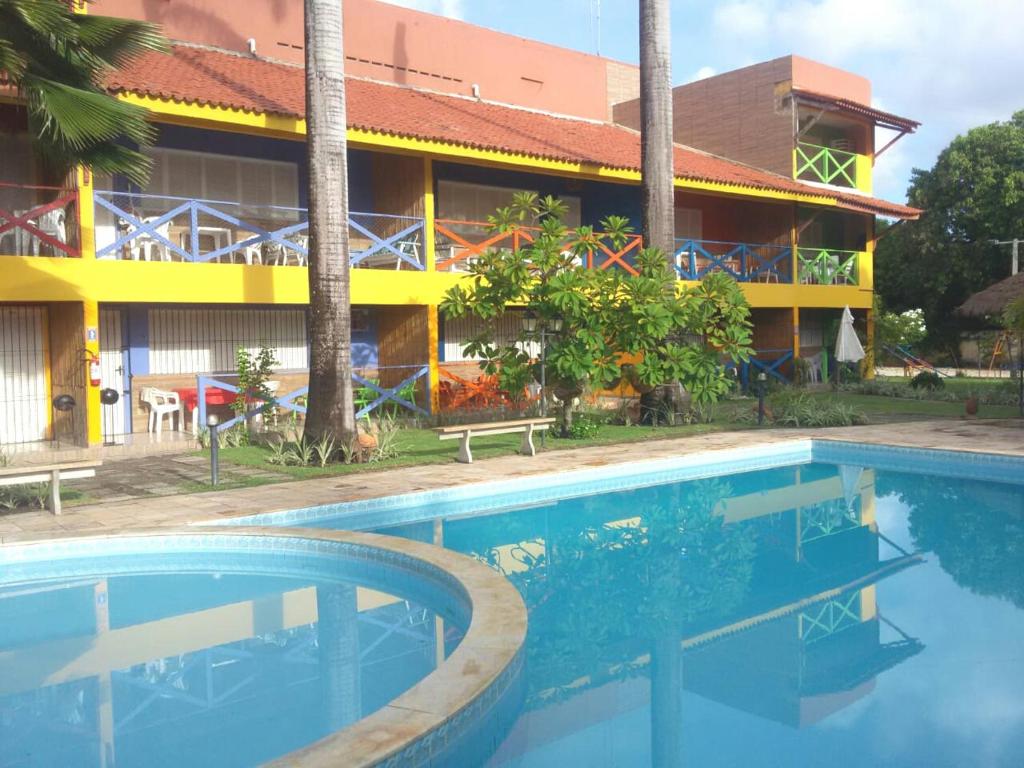 a hotel with a swimming pool in front of a building at Pousada Recanto do Sossego in Itamaracá